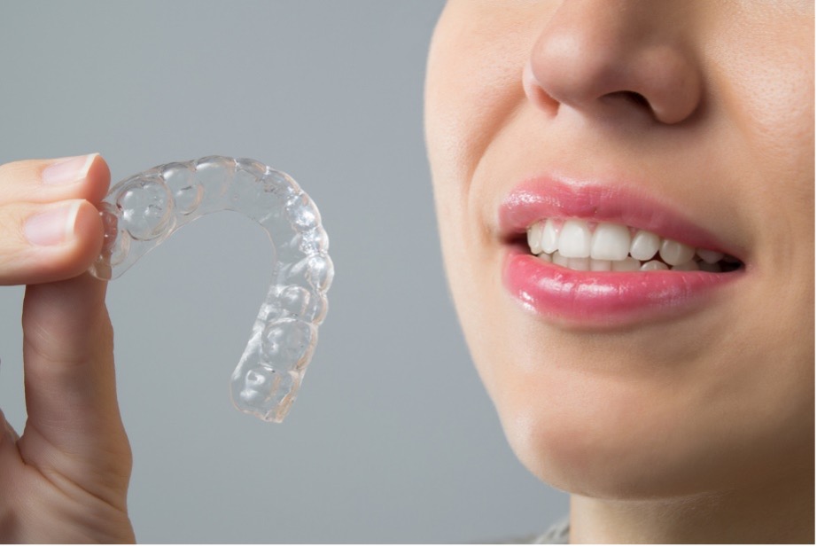 Person smiling holding Clear Aligners
