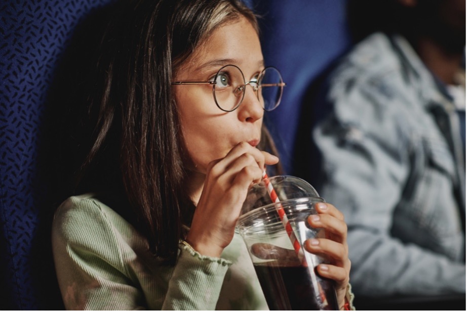 A person drinking from a glass of cola
