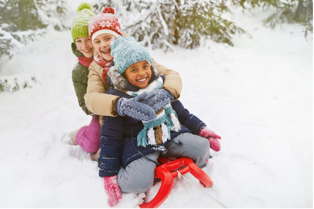 A group of children on a sled in the snow, Dashing Through the Snow: 12 Orthodontic Tips for a Winter Wonderland Smile