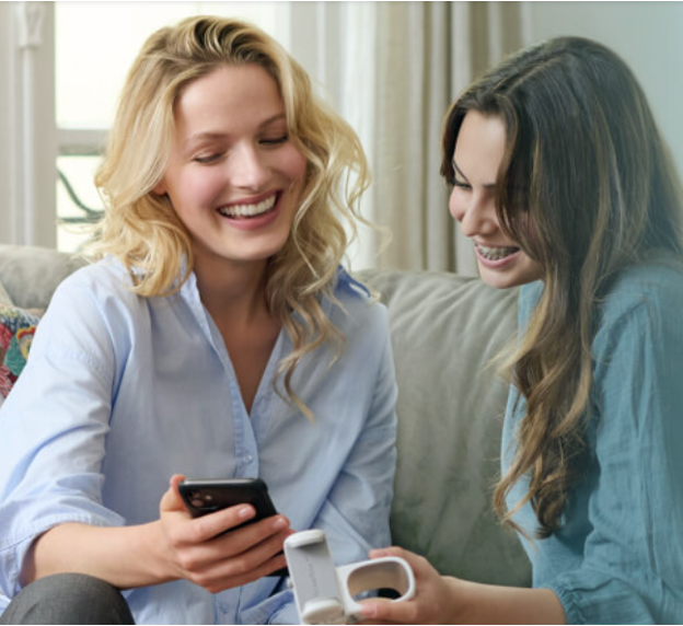 A couple of women sitting on a couch looking at a phone, Digital Orthodontic Monitoring