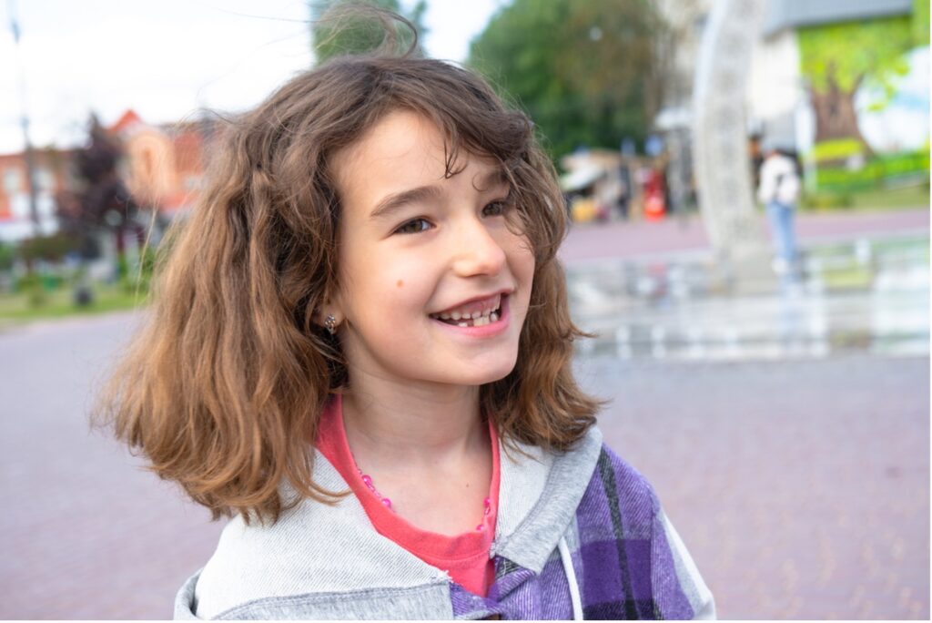 A child smiling at the camera, outdoors, When The Tooth Fairy Misses: Understanding Missing Permanent Teeth in Kids