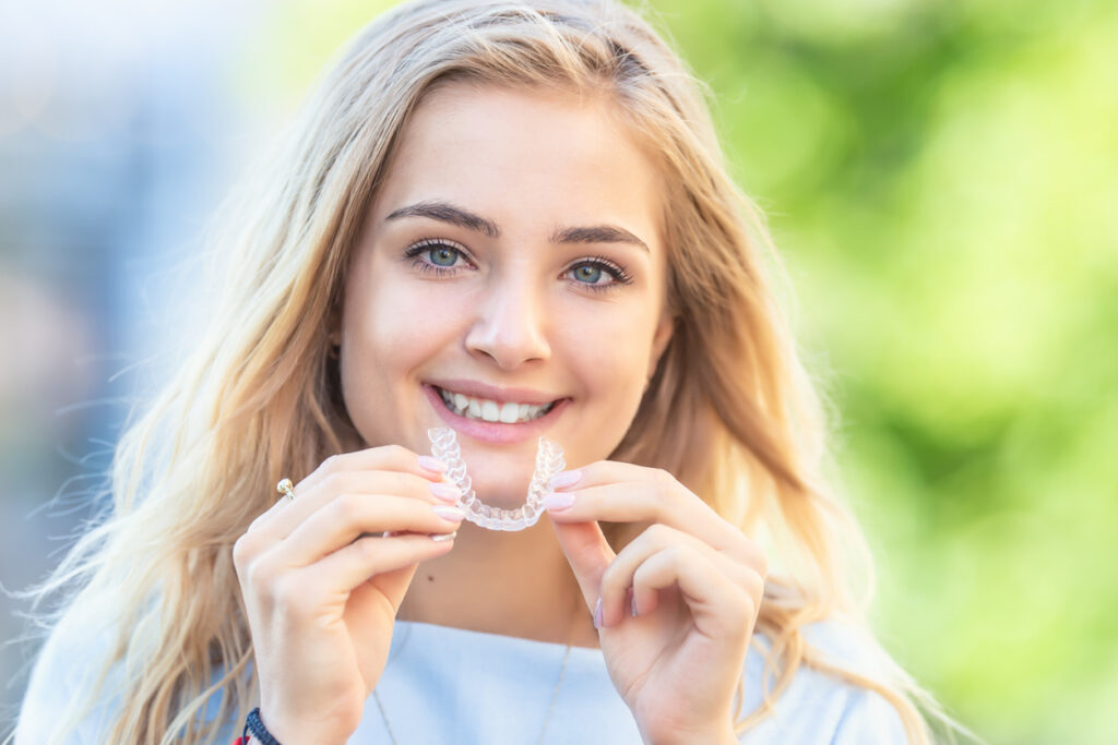 A person smiling with clear plastic braces, Clear Aligners for Students at McDonough Orthodontics